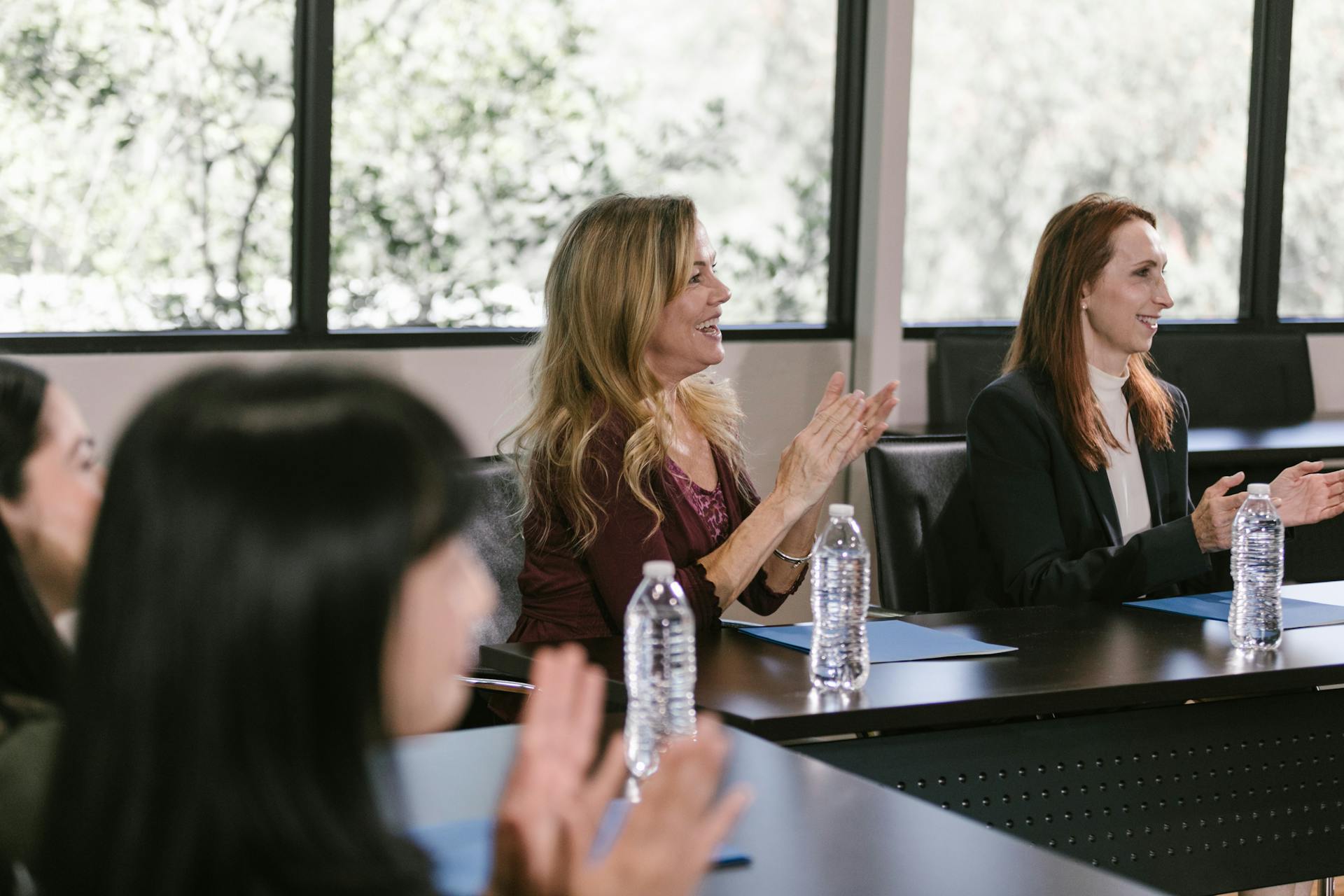 Focused business professionals clap during a conference meeting, capturing positive engagement.