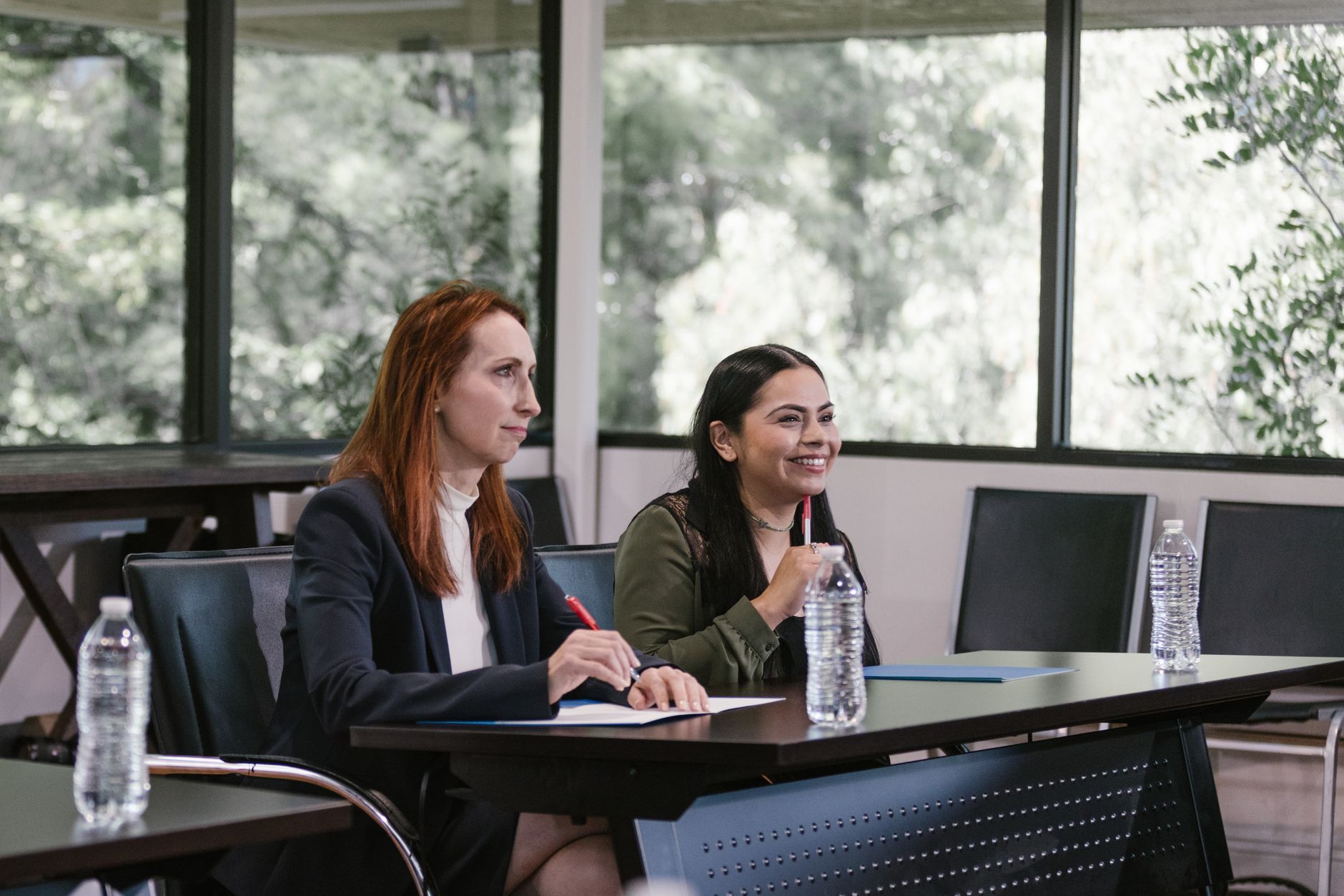 Two professional women engaged in a business meeting in a bright, modern conference room.
