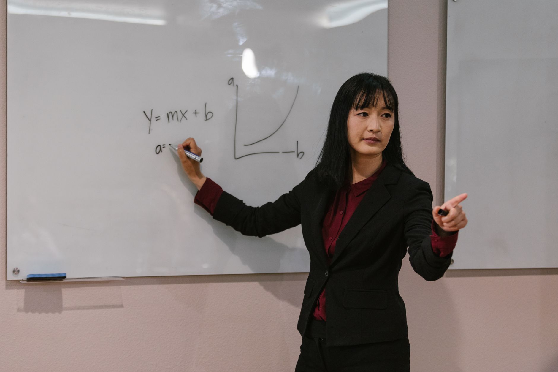 Female teacher explaining mathematical graph on whiteboard during a lesson.