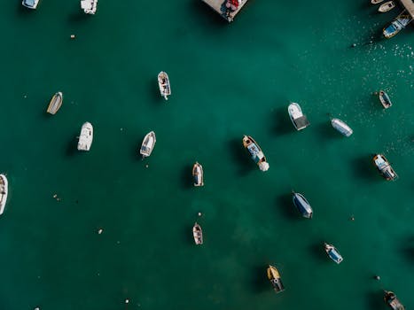 Aerial shot of diverse boats floating in the turquoise waters of Marsaxlokk harbor, Malta.