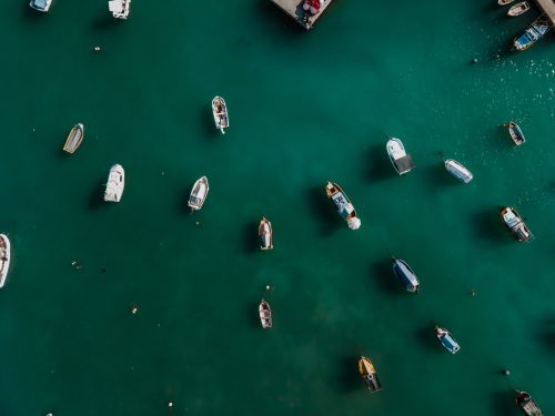 Free Aerial shot of diverse boats floating in the turquoise waters of Marsaxlokk harbor, Malta. Stock Photo