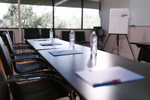 Free Spacious conference room with water bottles and notes on a wooden table ready for a meeting. Stock Photo