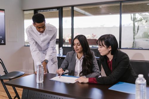 Free Three professionals discussing a project in a modern conference room setting. Stock Photo
