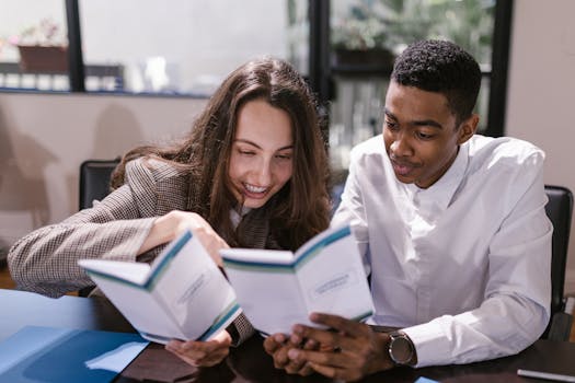 Two colleagues, a woman and a man, engaging in reading at an office setting.