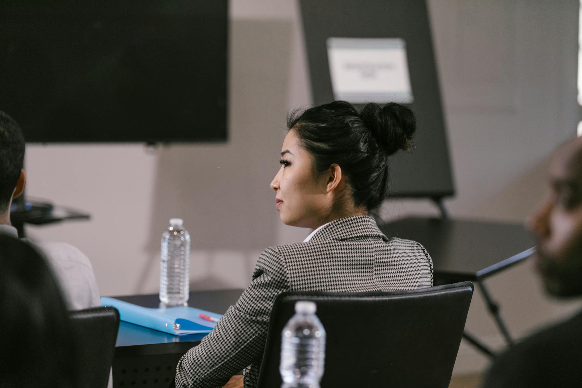 Asian woman in corporate attire attending a business meeting in a conference room.