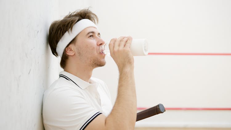 Side View Of A Squash Player Drinking Water