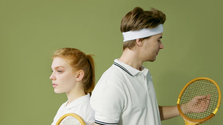 A Man And A Woman In White Polo Shirts Holding Tennis Rackets