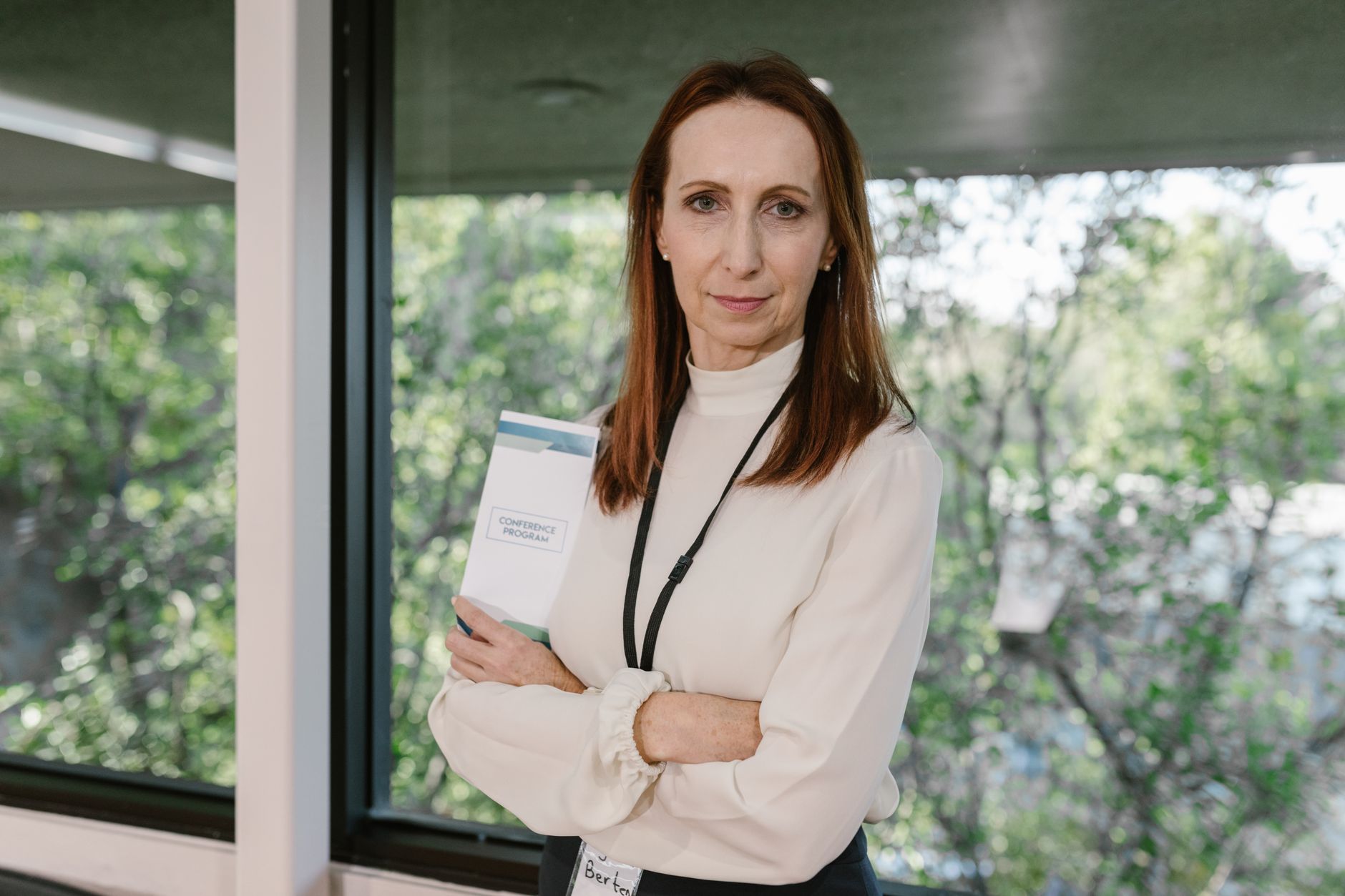 Serious businesswoman standing confidently with a conference program in an office setting.