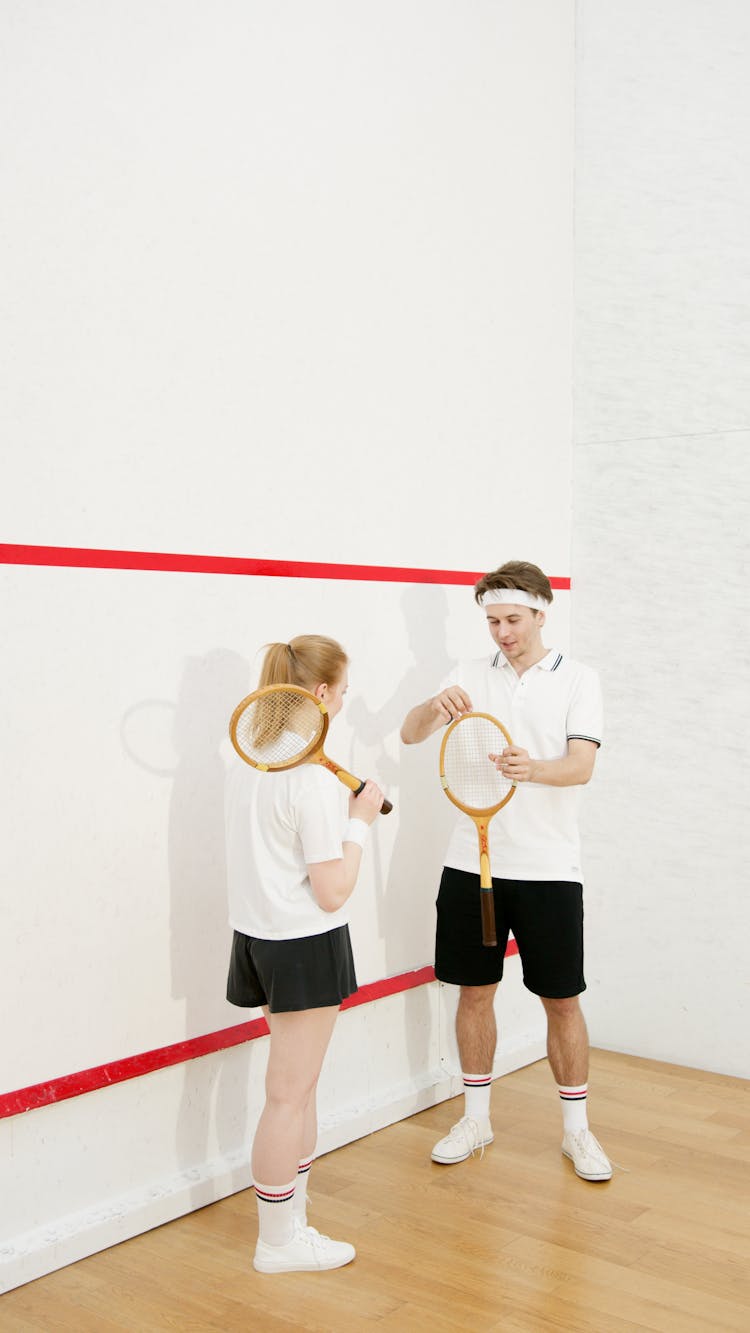 Man And Woman Holding Tennis Rackets