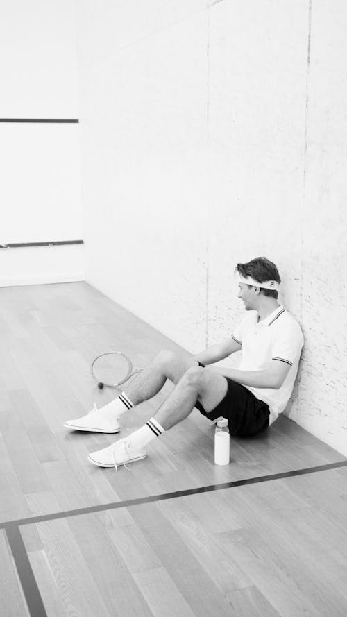 Free Man Sitting on the Floor After Tennis Match Stock Photo