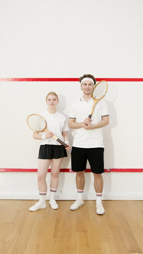Free Man and Woman in White T-shirts Holding Tennis Rackets Stock Photo