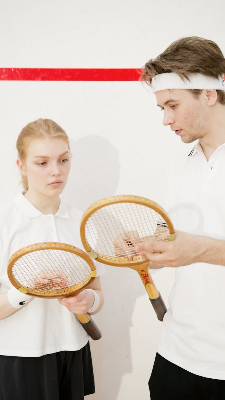 A Man And A Woman Holding Tennis Rackets