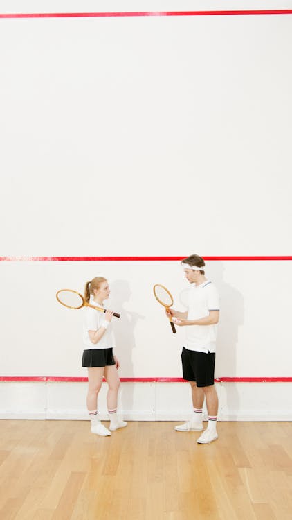 Free Man and Woman Standing in Front of Each Other and Holding Tennis Rackets  Stock Photo