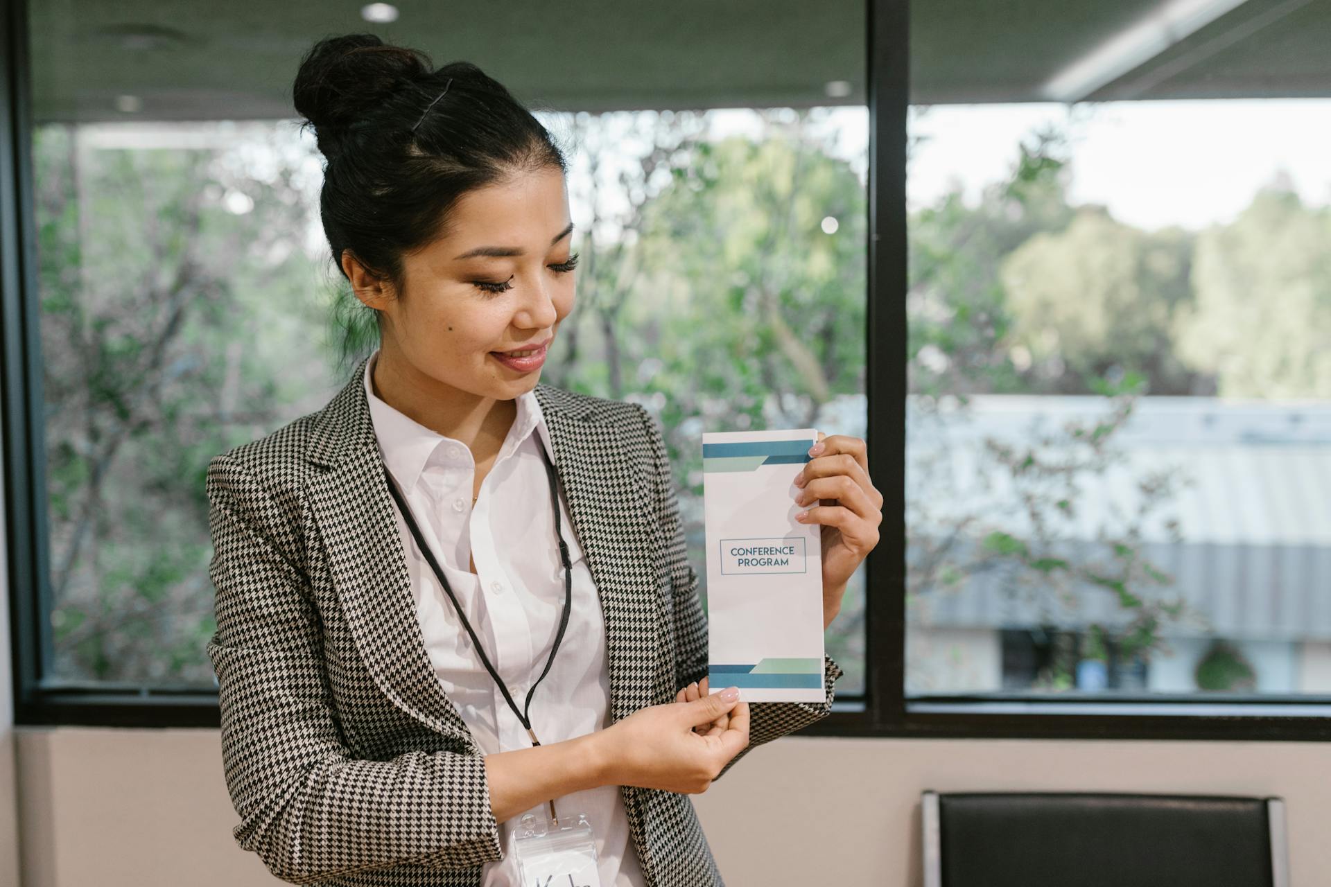 Young professional woman holding a conference program brochure indoors.