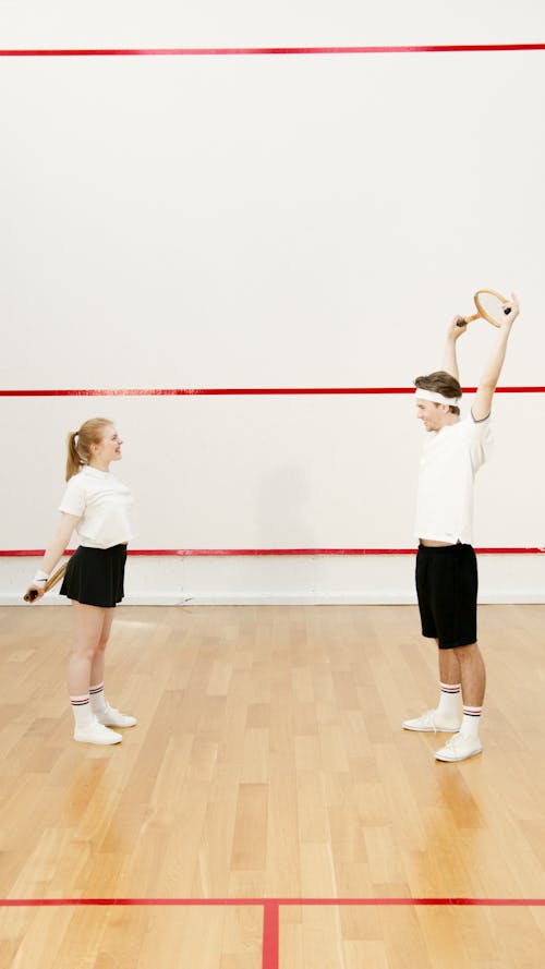 Free A Couple Stretching While Holding Squash Racket on the Wooden Court Stock Photo