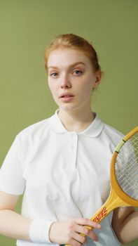 Young woman tennis player in white shirt holding a wooden racquet.