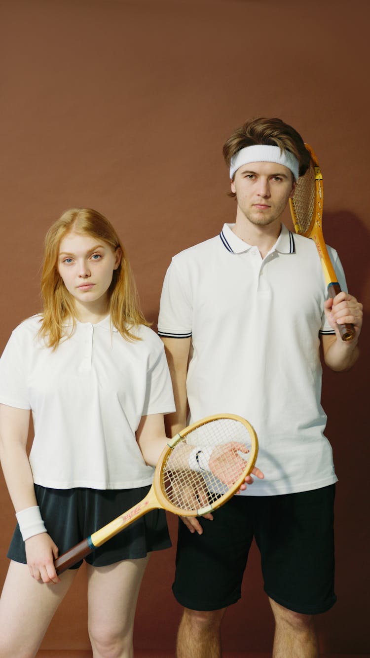 A Man And A Woman Holding Tennis Rackets