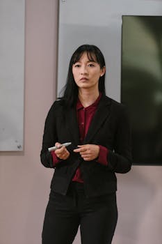Confident woman in corporate attire standing in front of a presentation screen.