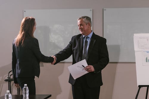 Free Man Holding a Document Shaking Hands with a Colleague Stock Photo