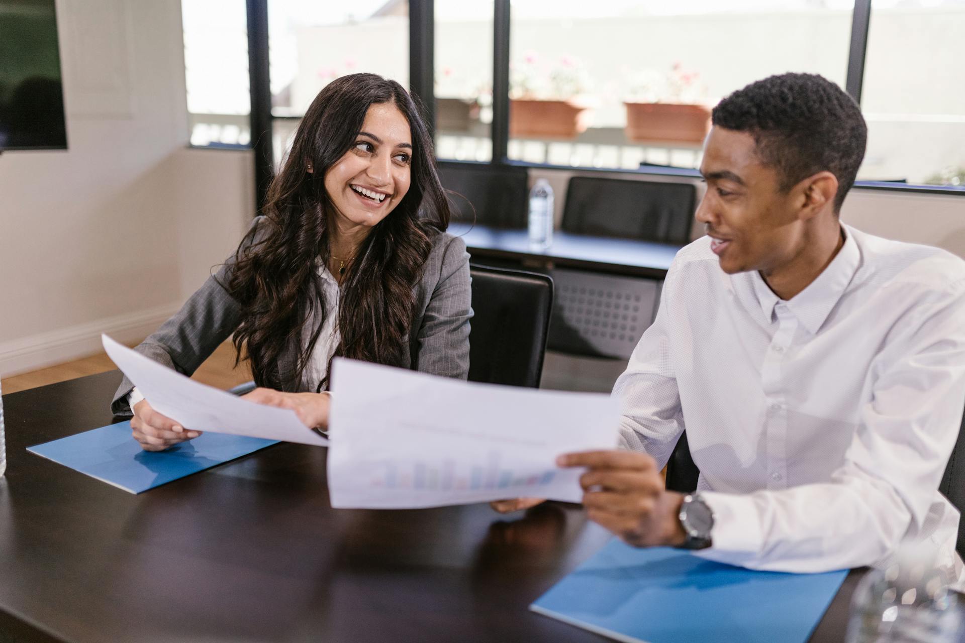 Two colleagues discussing business analytics in a modern office environment, fostering teamwork and diversity.