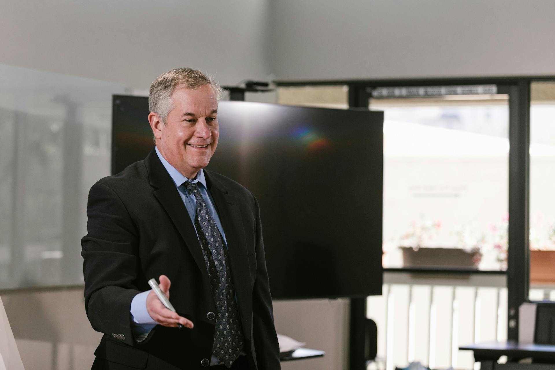 Smiling Man in a Black Suit Holding a Marker