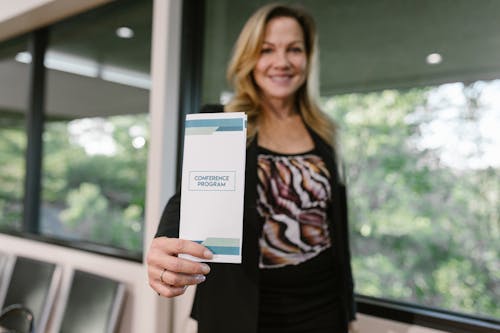 Free A Woman Holding a Conference Program Pamphlet Stock Photo
