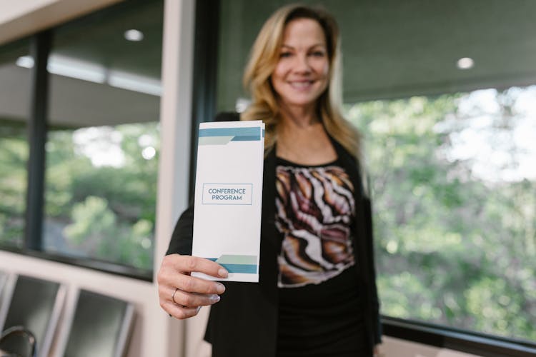 A Woman Holding A Conference Program Pamphlet