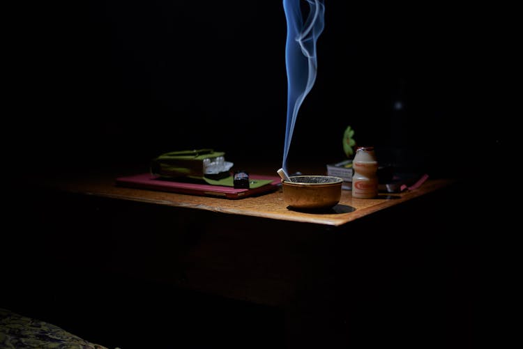 Brown Ashtray With Cigarette Casting Smoke On Table