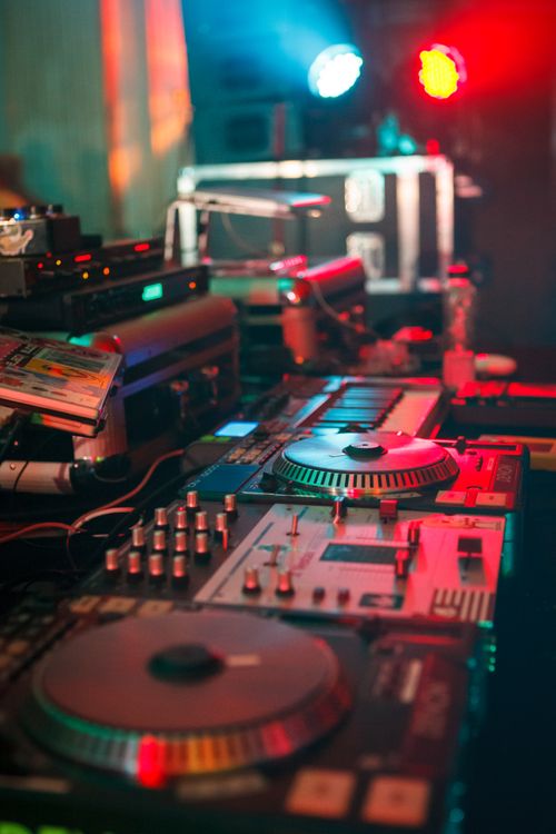 Free Dynamic DJ booth with colorful lights highlighting turntables and mixers in a club setting. Stock Photo