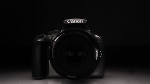 Free Minimalist black and white portrait of a DSLR camera with lens cap on a dark background. Stock Photo