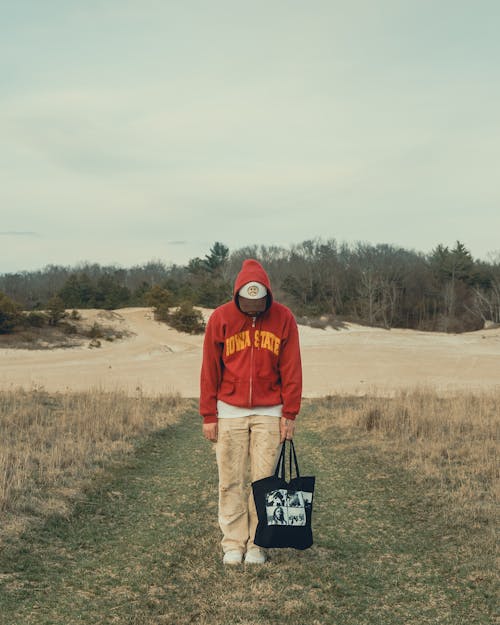 Photo of a Man with a Cap Holding a Black Bag