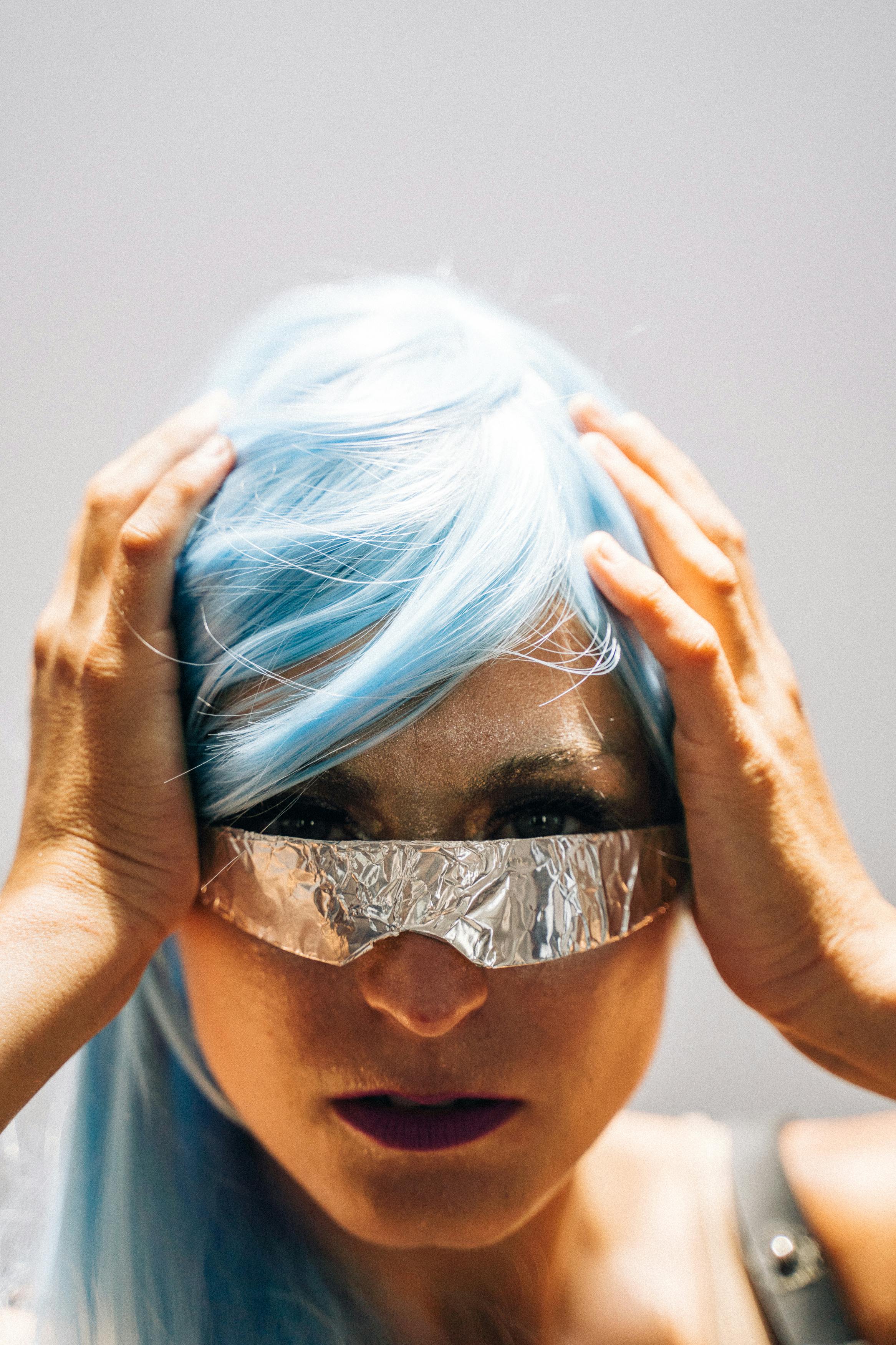Explore an intense portrait of a futuristic woman with blue hair and silver eyewear, embodying cyberpunk style.