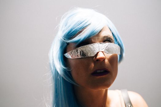 Close-up of a woman with blue hair and foil eyewear, exuding a cyberpunk vibe.