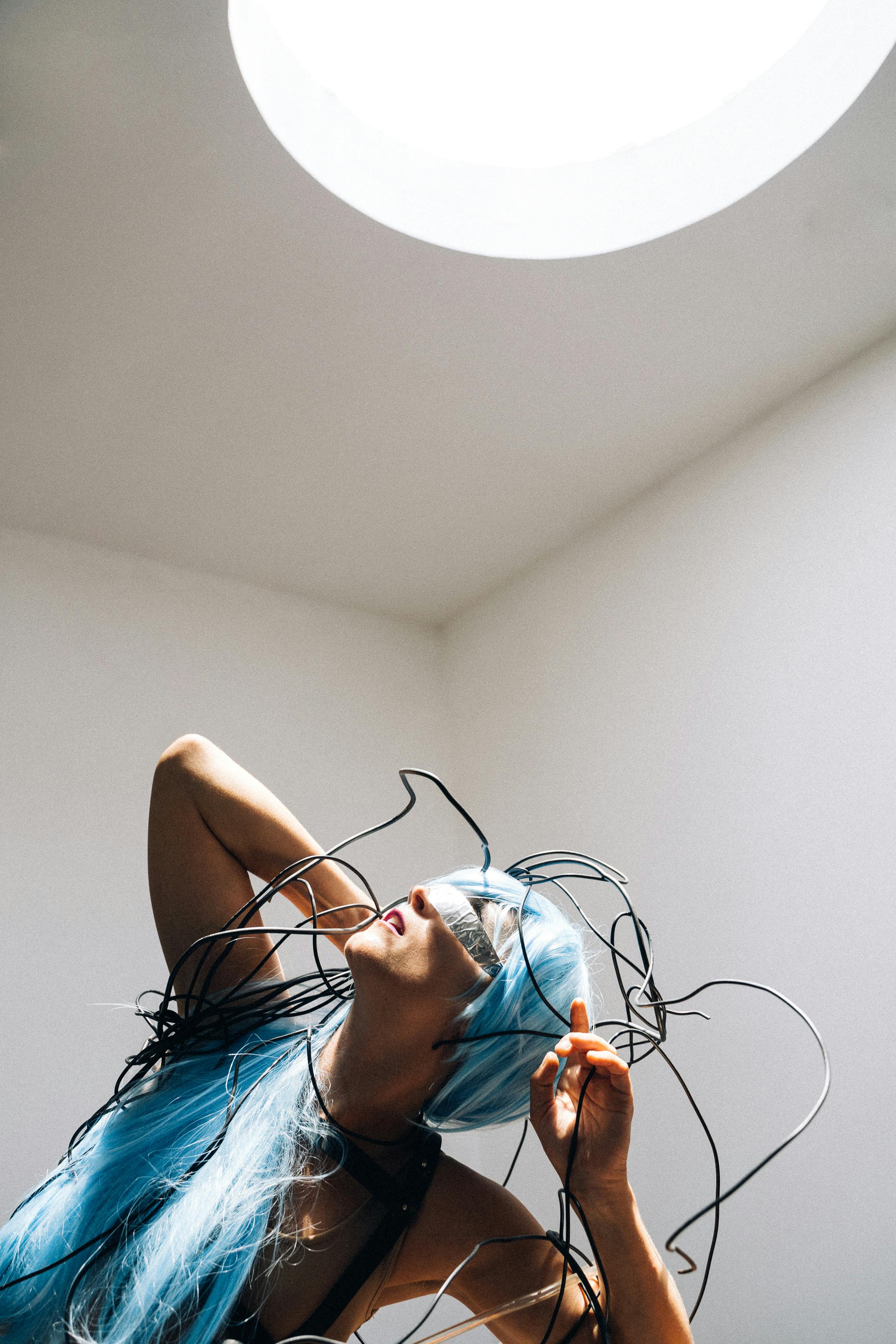 woman wearing a blue wig staring at the light