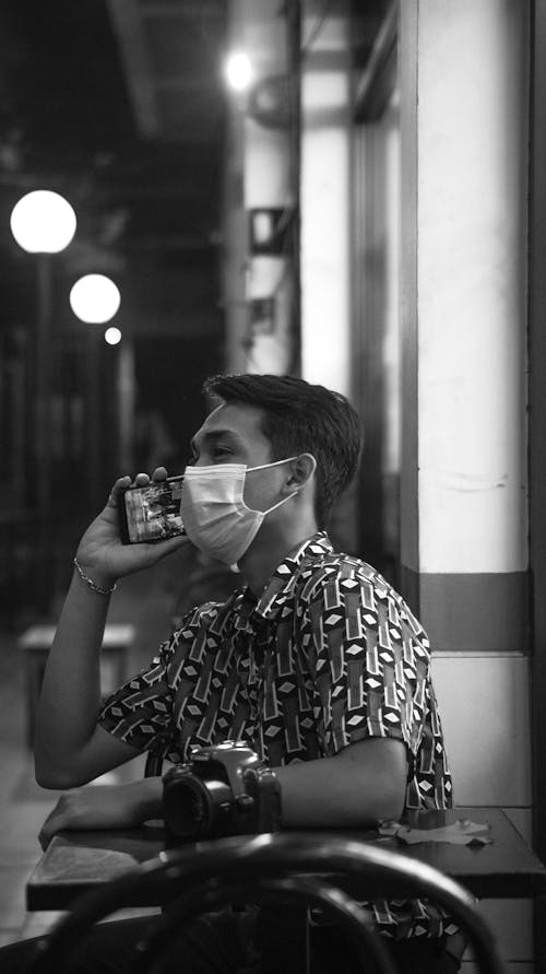 Grayscale Photo of a Man with a Face Mask Talking on the Phone