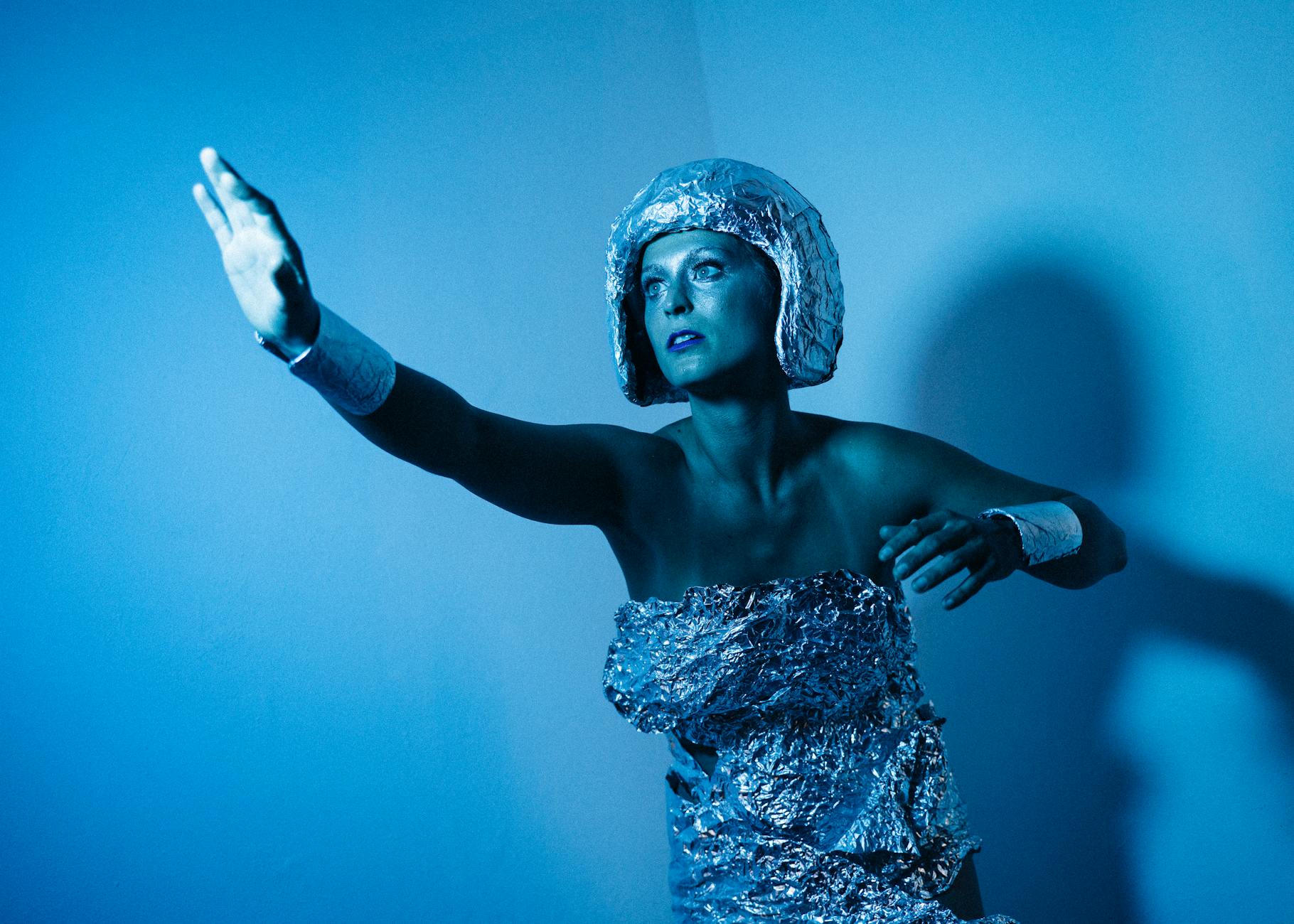 A futuristic woman in a metallic outfit poses in a cyberpunk setting, embracing sci-fi aesthetics.