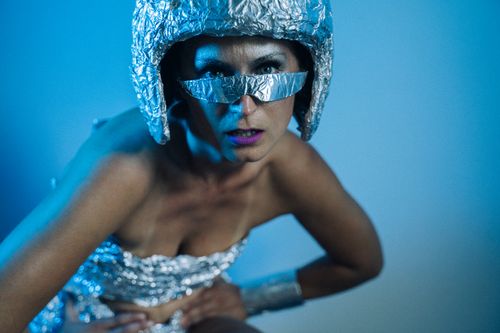 Free A futuristic-themed woman in metallic attire posing under blue lighting in a studio setting. Stock Photo