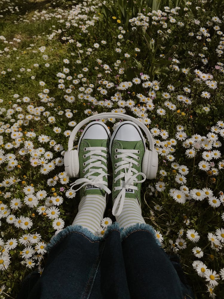 Woman Chilling In Meadow With Headphones On Legs