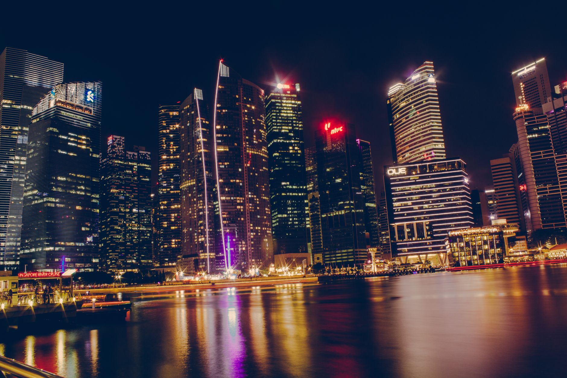 Stunning cityscape of Singapore's illuminated skyline reflecting on the water at night.