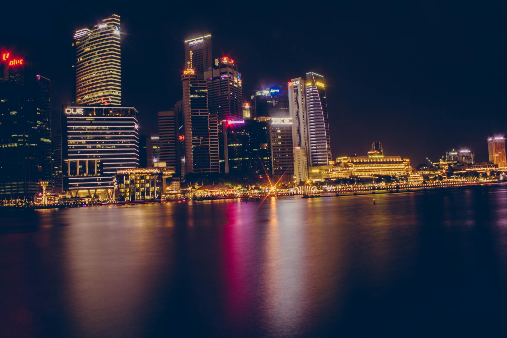 Stunning view of the illuminated Singapore cityscape reflecting on water at night.