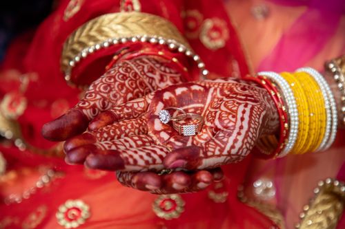 Free Close-up of bridal hands adorned with mehndi, holding rings with colorful bangles. Stock Photo
