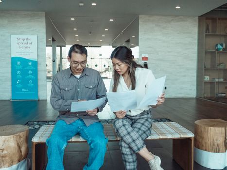 Two business colleagues discussing documents in a modern office setting.