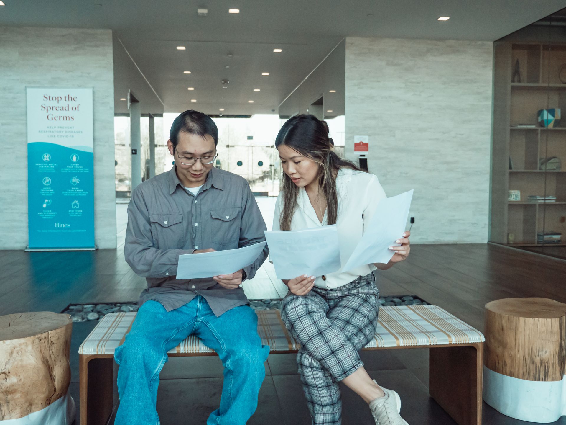 Two business colleagues discussing documents in a modern office setting.