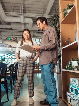 Two colleagues engaged in a casual discussion at an office workspace.