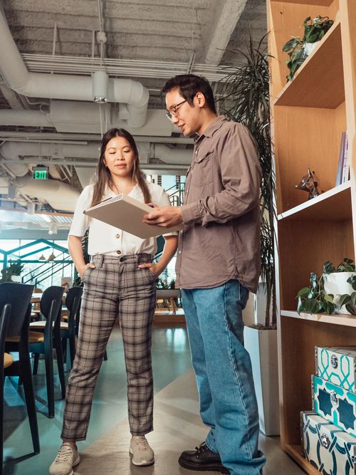 Free Two colleagues engaged in a casual discussion at an office workspace. Stock Photo