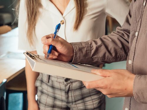 Free A person writing on a clipboard with a ballpen in an office setting. Stock Photo