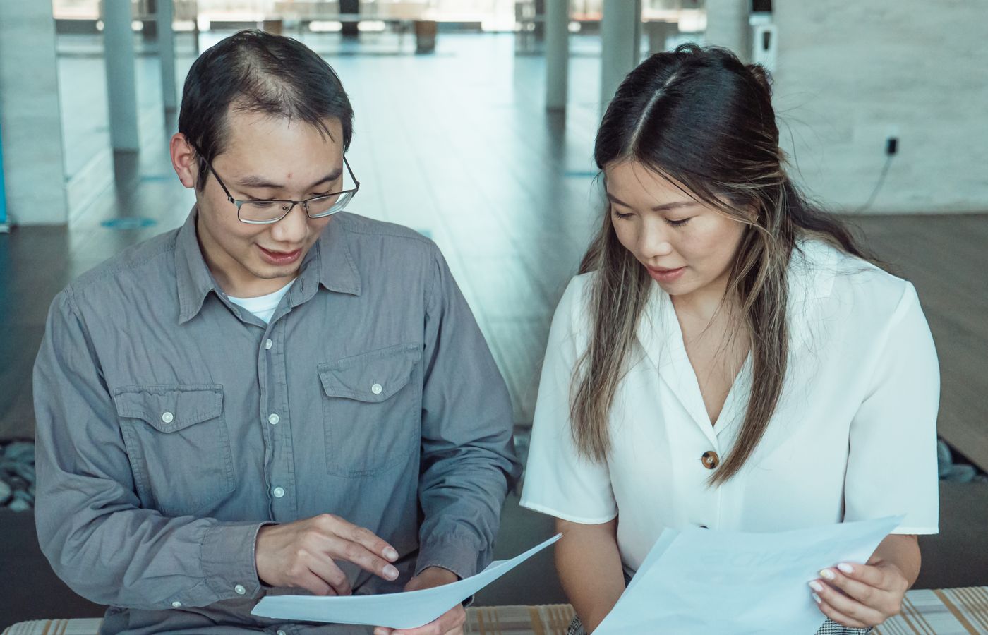 Two coworkers reviewing documents in a modern office, focused on teamwork and planning.