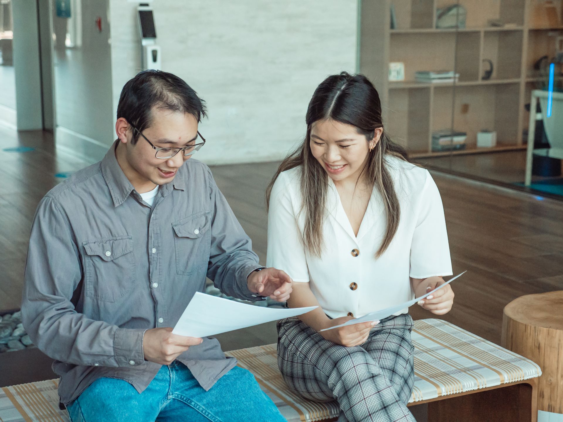 Two colleagues having a discussion while reviewing documents in a modern office setting.