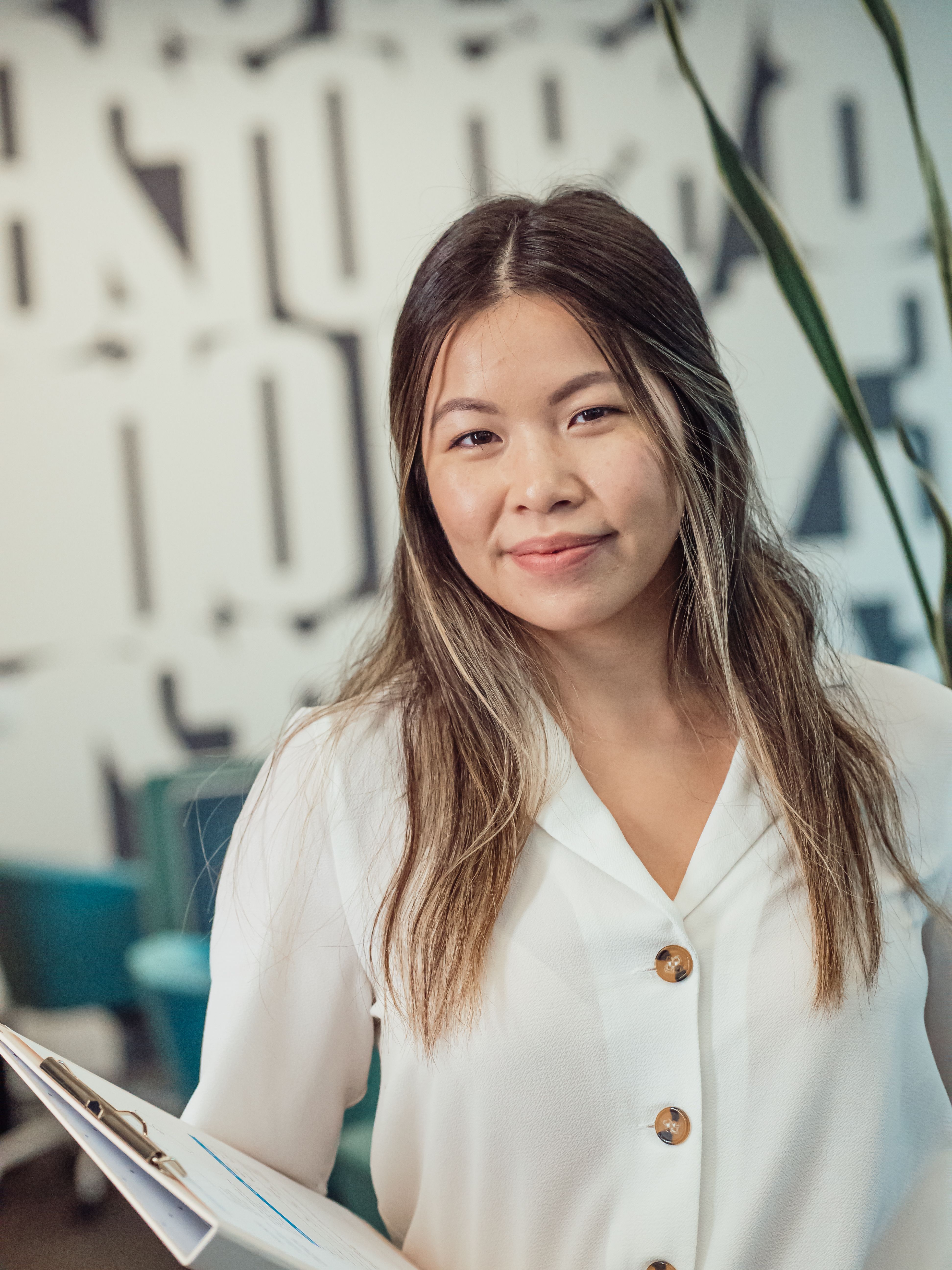 Confident businesswoman in white blazer smiling in an office setting.
