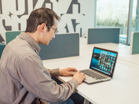 Asian man working on a laptop in a modern office environment. Professional and productive workspace setting.